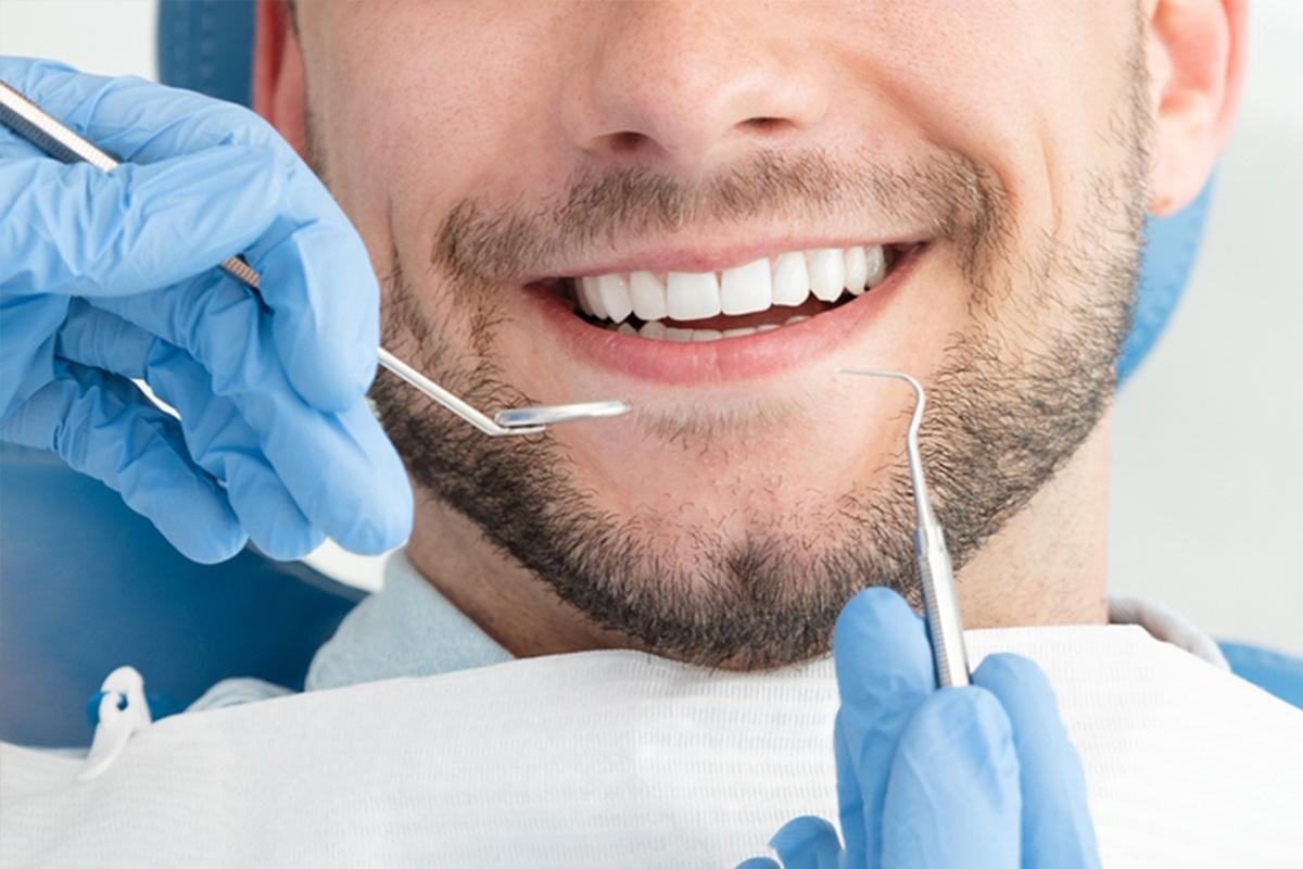 A smiling man enjoys a teeth whitening session while getting his teeth cleaned in Palm Desert, CA<br />
