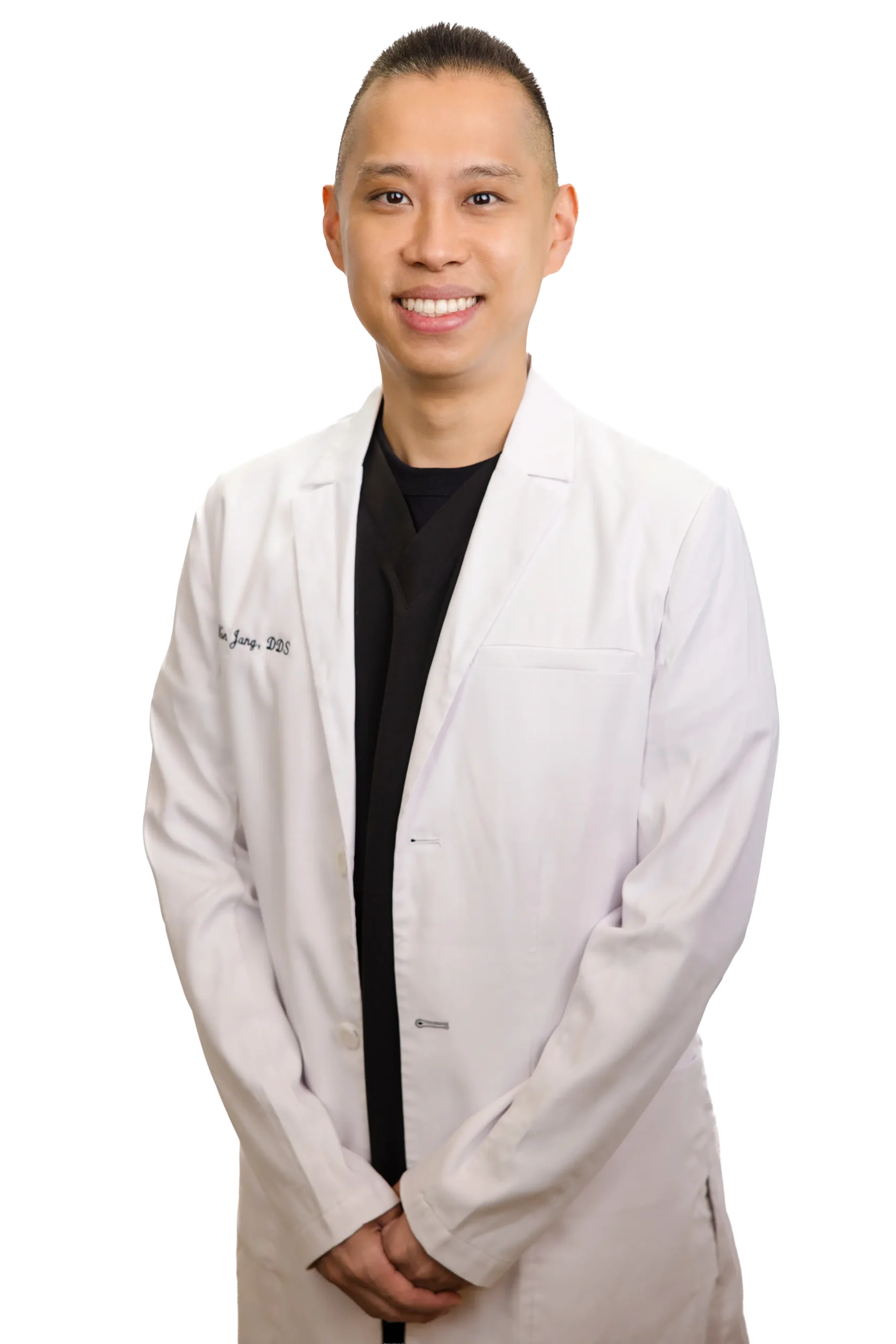 A person with long, red hair and a friendly smile is wearing a white lab coat over a black top, with arms crossed.